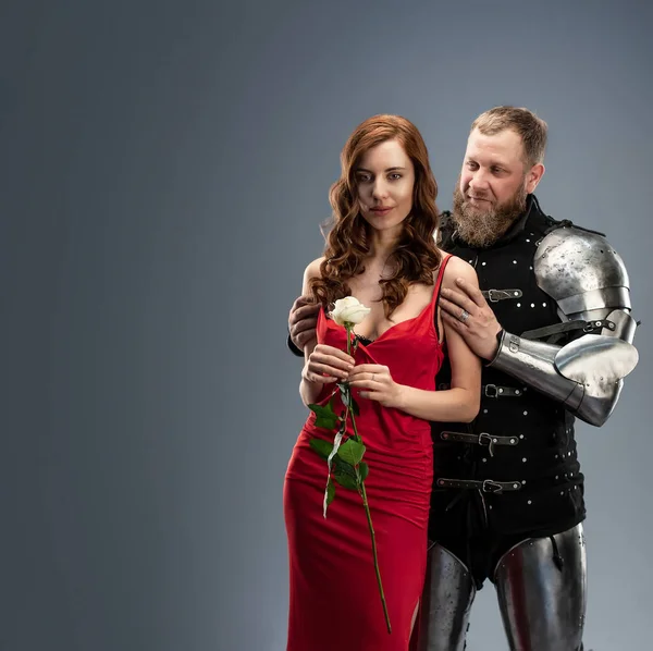 Όμορφο κορίτσι με κόκκινο φόρεμα και ιππότης με πανοπλία. — Φωτογραφία Αρχείου