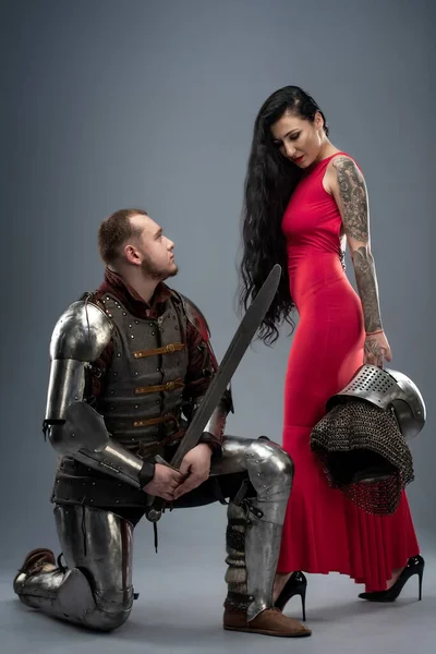 Belle fille dans une robe rouge et chevalier en armure — Photo