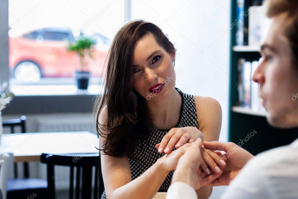 beautiful couple in a cafe at a table drinks coffee smiling at each other