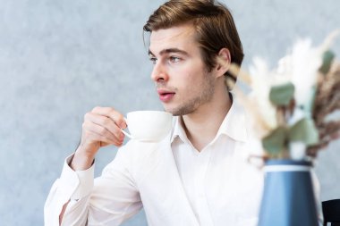 Beyaz gömlekli yakışıklı bir erkek kafeteryada oturmuş, planlarını düşünüyor. Kafkasyalı bir adam kafeteryada buluşmayı bekliyor. Boş zamanların hayalini kuruyor.