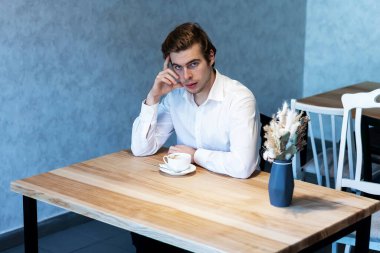 Beyaz gömlekli yakışıklı bir erkek kafeteryada oturmuş, planlarını düşünüyor. Kafkasyalı bir adam kafeteryada buluşmayı bekliyor. Boş zamanların hayalini kuruyor.