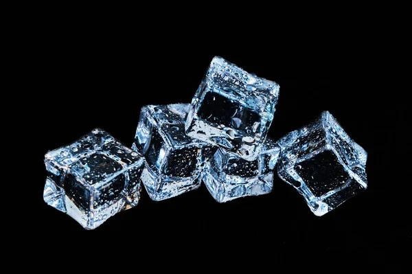 Cubos de hielo en gotas de agua sobre un fondo negro — Foto de Stock