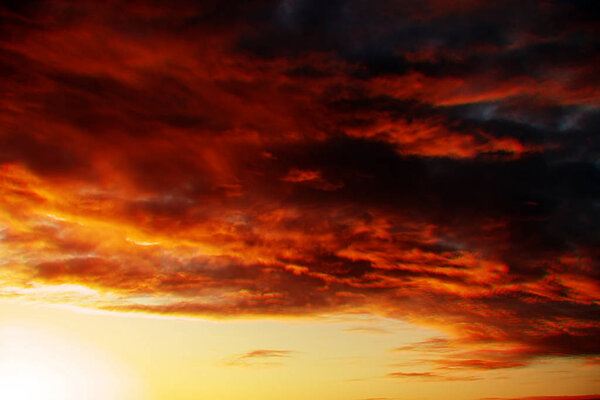 Dramatic fiery sunset sky in a mixture of golden, red, orange and black colors
