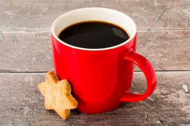 Siyah kahve ve Noel Yıldızı Kurabiyesi ile dolu kırmızı bardak.