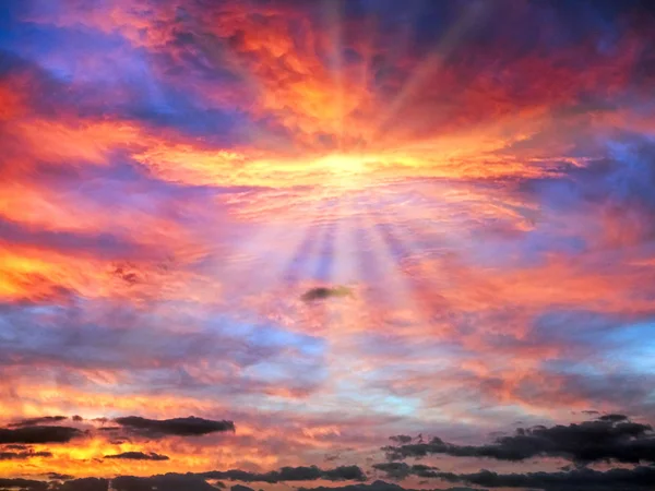 Céu de nascer do sol nublado em azul, vermelho, laranja, amarelo com raios de sol — Fotografia de Stock