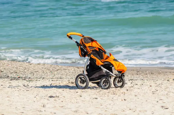 empty stroller stands on the sand, on the beach, near the ocean
