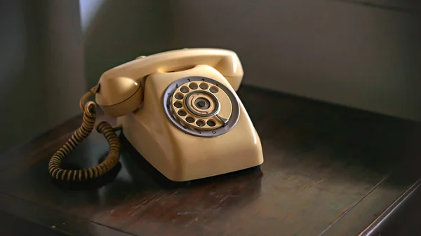 Altes hellbraunes Telefon auf braunem Holztisch im Licht der — Stockfoto