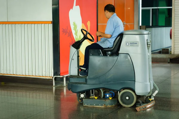 Worker cleaning store floor with machine — Stock Photo, Image