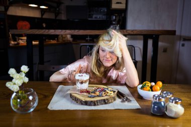 Komik sarışın masada yemek ile oturuyor.