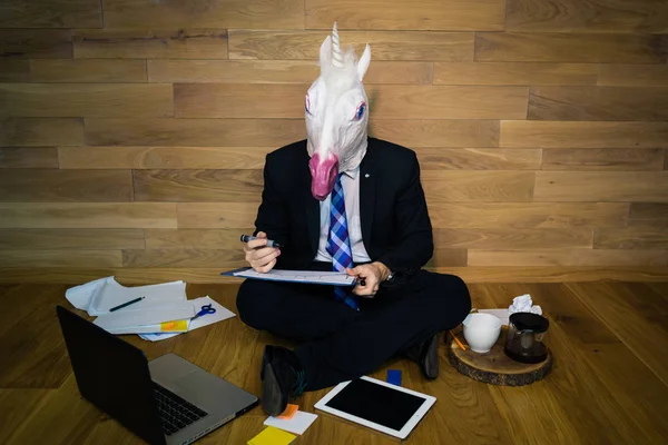 Young man wearing rubber mask sits on the floor