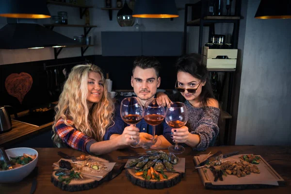 Três amigos atraentes sorrindo e jantar juntos — Fotografia de Stock