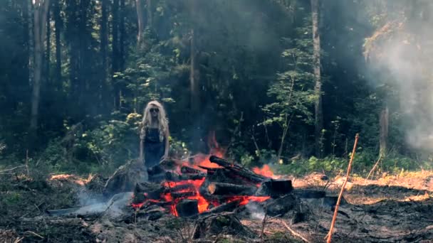 Una joven mujer se para cerca del fuego y levanta las manos y las baja — Vídeo de stock