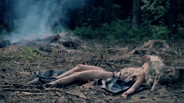 Сексуальная девушка загорает на фоне костра и веток — стоковое видео