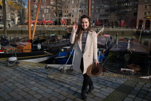 Joven hermosa mujer está sonriendo y de pie cerca del viejo puerto deportivo en Rotterdam — Foto de Stock