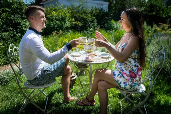 Duas pessoas sorridentes se senta à mesa com chá e doces no verão dia quente — Fotografia de Stock