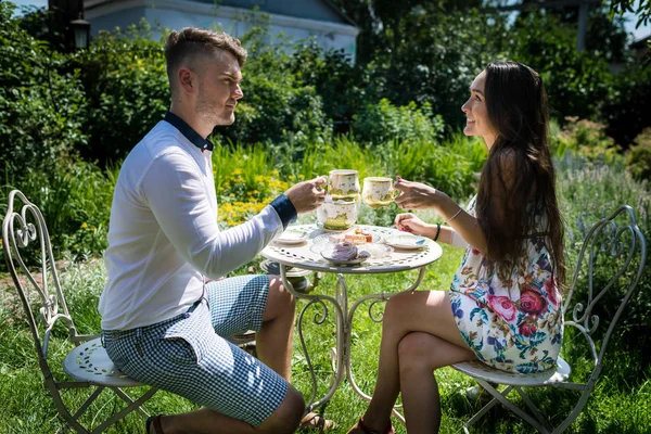 Homem com namorada senta-se à mesa elegante com chá e doces — Fotografia de Stock