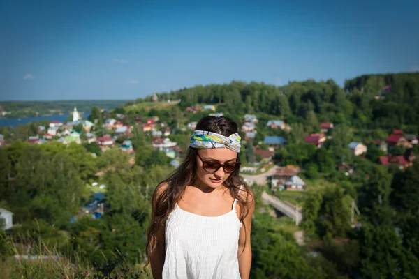 Mujer joven en gafas de sol y vendaje en la cabeza se encuentra en una colina — Foto de Stock