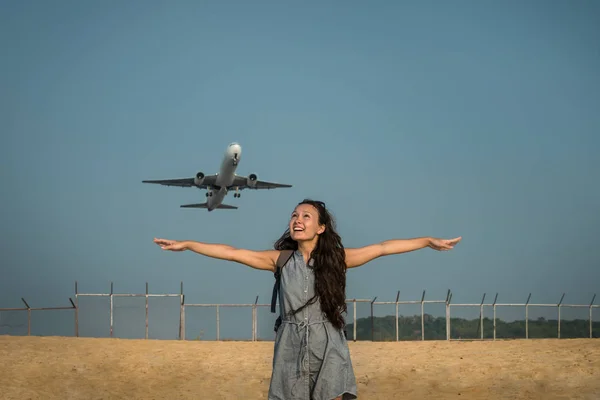 Viajero femenino está de pie en la playa y mirando en el avión — Foto de Stock