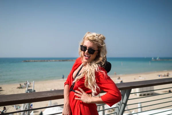 Joven mujer sonriente en vestido rojo brillante y gafas de sol — Foto de Stock