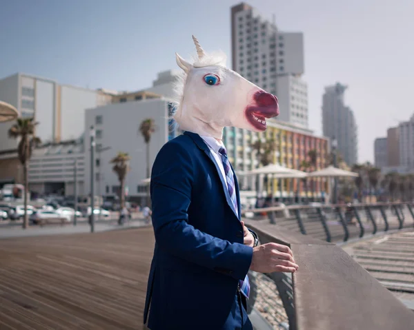 Gerente inusual en máscara divertida y traje se encuentra en el paseo marítimo de la ciudad — Foto de Stock