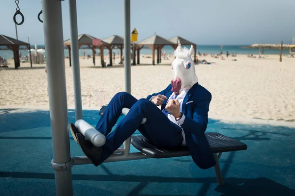 Szokatlan férfi öltöny és ló maszk sportolás közelében a strand — Stock Fotó