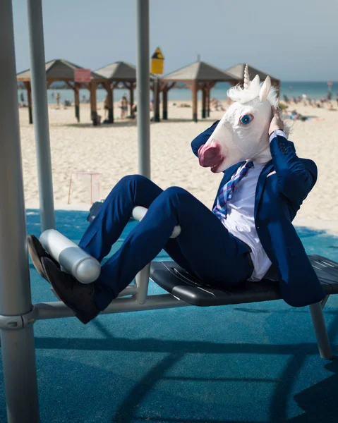Komikus férfi öltöny és vicces maszk sportot közelében a tengerparton — Stock Fotó