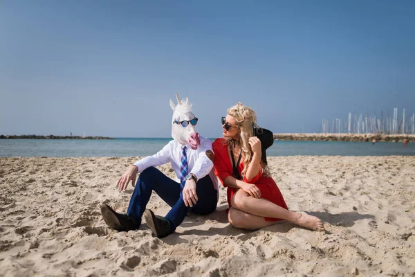 Joven hombre de traje se sienta con la mujer de moda en la playa — Foto de Stock