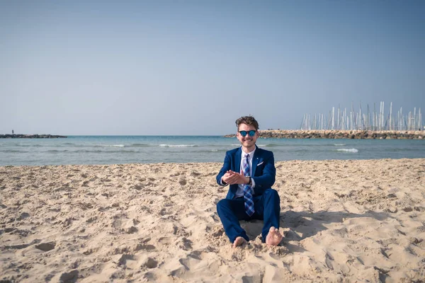 Hombre joven inusual en traje elegante se relaja en la playa y sonríe . — Foto de Stock