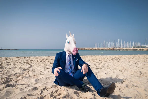 Joven con máscara divertida se sienta en la arena y disfruta de las vacaciones — Foto de Stock