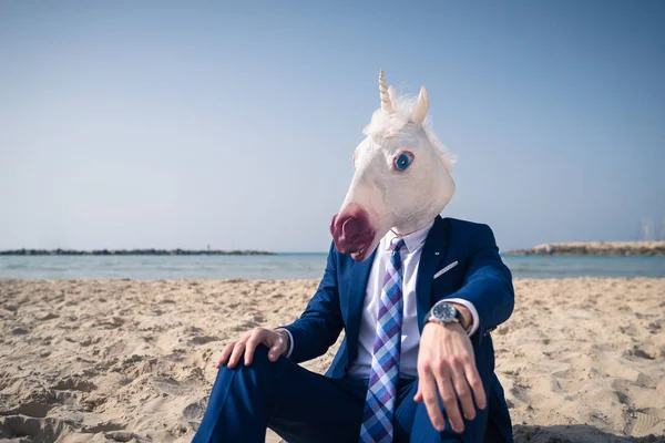 Trendy uomo in maschera divertente si siede sulla sabbia e gode di vacanza — Foto Stock