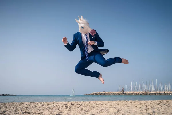 Elegante manager en máscara divertida y elegante traje salta a la playa — Foto de Stock