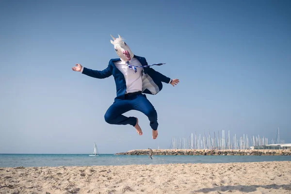 Hombre con estilo en máscara divertida y elegante traje salta en la playa — Foto de Stock