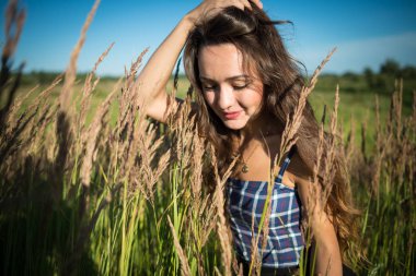 Çim sahada yaz günü içinde duran genç kadın.