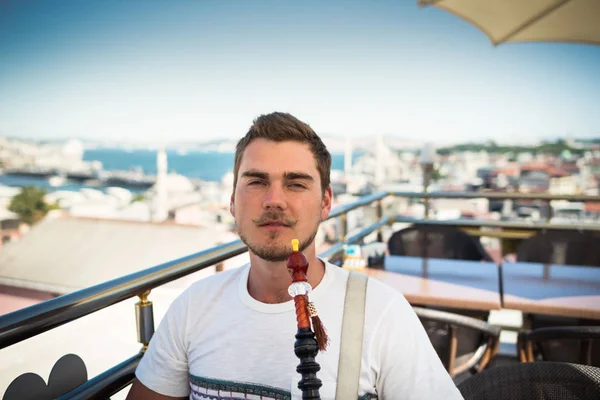 Un joven guapo con bigote fuma una cachimba en la terraza — Foto de Stock