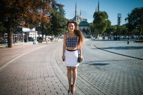 Young smiling woman is jumping at square on background of mosque and trees — Stock Photo, Image