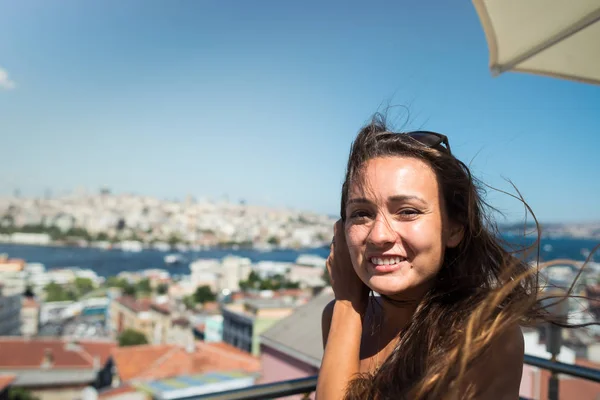 Joven mujer bonita se sienta en la terraza con hermosa vista en el paisaje urbano — Foto de Stock