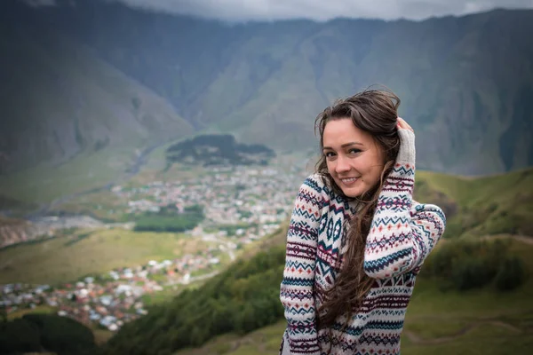 Joven mujer feliz se encuentra en el fondo de una pequeña ciudad en el valle — Foto de Stock