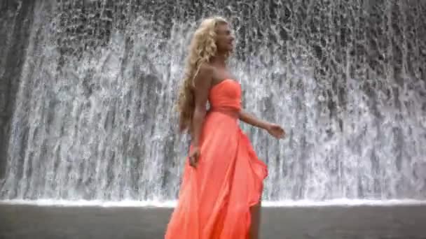 Joven Mujer Hermosa Vestido Naranja Caminando Sonriendo Fondo Gran Cascada — Vídeos de Stock