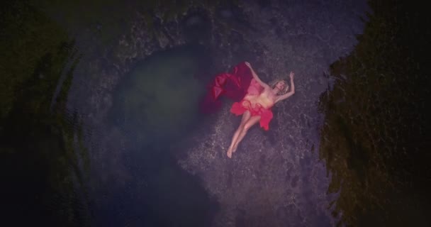 身穿粉色衣服的年轻女子独自躺在石头和岩石旁边的天然水池里 从无人驾驶飞机上俯瞰 努沙佩尼达 印度尼西亚 — 图库视频影像