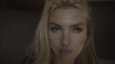 Modern bir dairede ayakta duran ve poz veren ciddi bir kadının yüzüne yakından bakın. Şık bir iç mekanda pencereden içeri bakan dalgın kız..