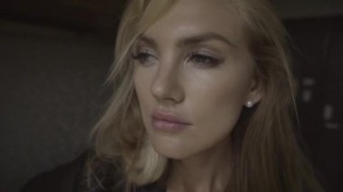 Modern bir dairede ayakta duran ve poz veren şehvetli genç bir kadının yüzüne yakından bakın. Şık bir iç mekanda pencereden içeri bakan dalgın kız..