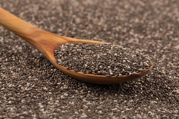 Chia seeds in a wooden spoon on chia background