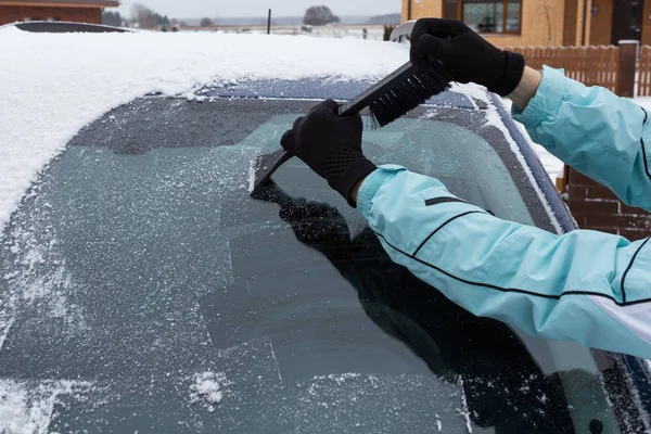 Vrouw schoonmaken sneeuw van de auto — Stockfoto
