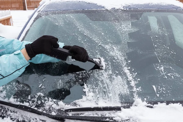 Vrouw schoonmaken sneeuw van de auto — Stockfoto