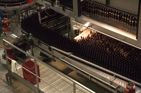 Interior de la fábrica de cerveza. Equipo para la cervecería. Línea transportadora con muchas botellas de cerveza. Flujo de trabajo de fábrica . —  Fotos de Stock