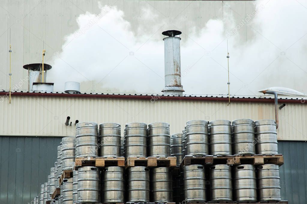 The exterior of the brewery. Workflow, smoke from the pipes. A large number of steel barrels. 