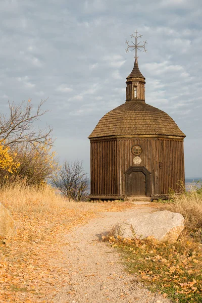 A small wooden church. The path leads to the church. Wooden church in a picturesque place. Chapel on the side of the river.