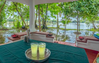 Arka planda Kerala Backwaters ile masada meyve suyu