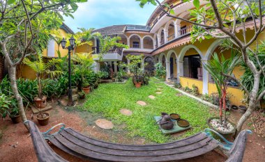 Ağaçlar ve ahşap banklarla çevrili Avlu