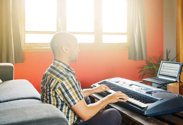 Man playing piano while taking online lessons